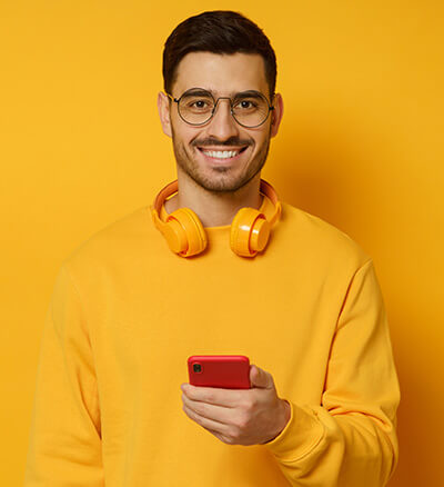 Hombre de camiseta amarilla sujeta un teléfono rojo y sonríe