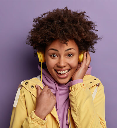 Mujer sonriente con audífonos amarillos y chaqueta amarilla
